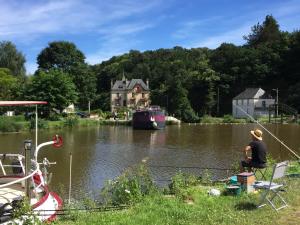 eine Person, die auf einem Stuhl sitzt und in einem Fluss angelt in der Unterkunft Villa Tranquillité in Rohan