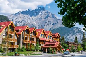 a building with red roofs with a mountain in the background at Moose Hotel and Suites in Banff