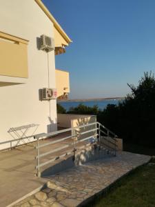 a house with a wooden bench on a patio at Apartments Nikola Caska in Novalja