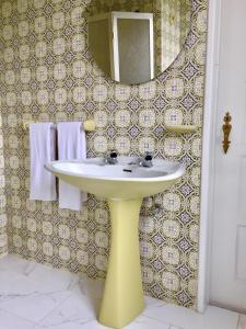 une salle de bains avec un lavabo jaune et un miroir dans l'établissement Cascais Seaside Garden Villa, à Cascais
