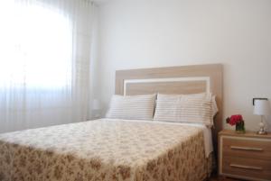 a white bedroom with a bed and a window at Casa La Torre in Isla de Arosa