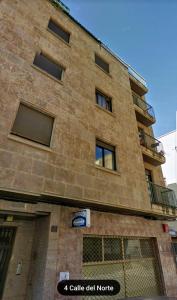 a tall brick building with a balcony on it at Apartamento Norte Comfort in Salamanca