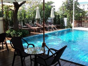 uma mesa com um guarda-sol ao lado de uma piscina em Suvarnabhumi Suite Hotel em Lat Krabang