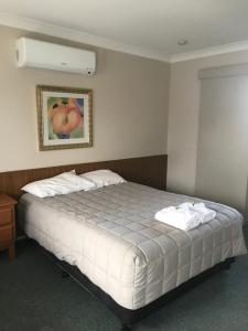Un dormitorio con una cama blanca con una foto en la pared en Kootingal Landview Motel en Kootingal