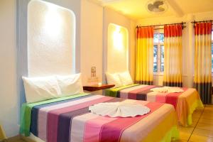 a hotel room with two beds with colorful blankets at Hotel Careyes Puerto Escondido in Puerto Escondido