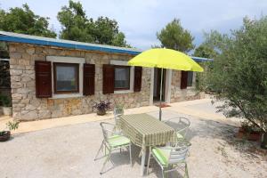 a table with a yellow umbrella in front of a house at House Car Mirko in Šilo