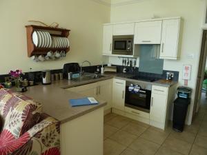 cocina con armarios blancos y encimera en 2A Redcliffe Apartment en Bishopston