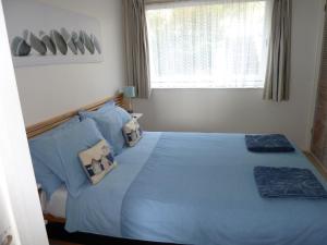 a bedroom with a blue bed with pillows and a window at 2A Redcliffe Apartment in Bishopston