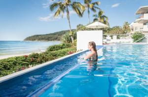 una mujer en una piscina al lado de la playa en Tingirana Noosa en Noosa Heads