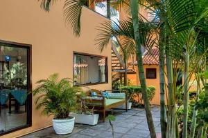 a patio with palm trees in front of a building at Pousada Happiness - Ferradura in Búzios