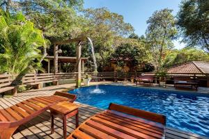 a swimming pool with two benches and a fountain at Pousada Happiness - Ferradura in Búzios