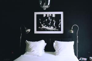 una camera da letto con un letto con cuscini bianchi e un quadro di Le Vaudeville a Bruxelles