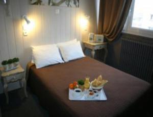 ブローニュ・シュル・メールにあるホテル ドゥ ロンドルのベッドに食料品のトレイを用意したホテルルーム