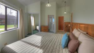 a bedroom with a large bed and a window at Ocean Breeze Cottages in Burnt Pine