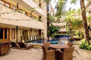 a hotel lobby with a pool and tables and chairs at Famous Hotel Kuta Formerly Permata Kuta Hotel in Kuta