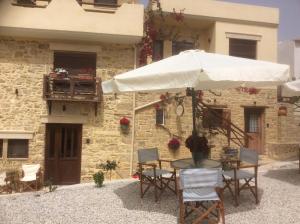 a table with an umbrella in front of a building at Kritikies 1 Kydonia in Pitsidia