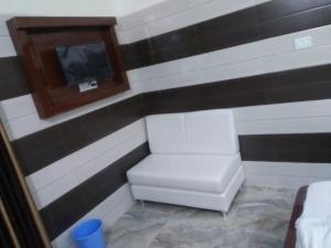 a room with a chair and a tv on a wall at Vidya Guest House in Katra