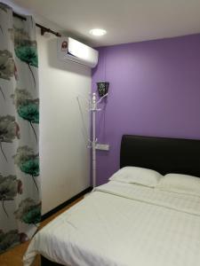 a bedroom with a white bed and a purple wall at Coral Home 珊瑚之家 in Semporna