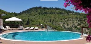 a swimming pool with chairs and a mountain at Paxos villas in Gaios