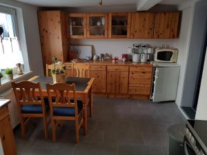 a kitchen with wooden cabinets and a table with chairs at Pension Bartoschewitz in Lenzen