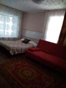 オレンブルクにあるApartment on prospekt Pobedyのベッドルーム1室(ベッド1台、赤いソファ付)