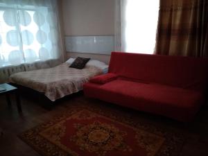 オレンブルクにあるApartment on prospekt Pobedyのベッドと赤いソファが備わる客室です。