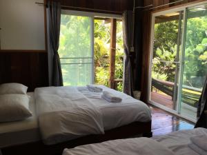 two beds in a room with a large window at Baan Suan La Moon in Chiang Khan