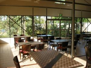 an empty restaurant with tables and chairs and windows at Pandanus on Litchfield in Batchelor