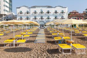 un mucchio di sedie e ombrelloni su una spiaggia di Hotel Marina a Lido di Jesolo