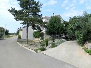 a white house with trees and a driveway at Apartmani Lucija Jurković in Malinska