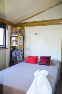 a bed with two red pillows in a room at Camping Routes du Monde ATC La Hume-Arcachon in Gujan-Mestras