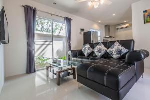 a living room with a black leather couch and a glass table at Thuan Resort in Rawai Beach