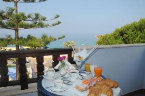 a table with a breakfast of croissants and orange juice at Beach Hotel in Diamante