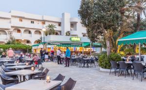 un restaurant avec des tables et des chaises en face d'un bâtiment dans l'établissement BLUESEA Club Martha's, à Cala d´Or