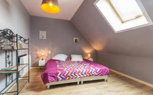 a bedroom with a bed with a purple bedspread and a window at Les Champs De La Mer in Auberville-la-Renault