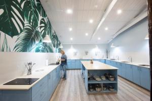 a woman standing in a kitchen with blue cabinets at Coral Divers in Sodwana Bay