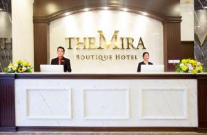 two people standing behind a counter in a hotel at The Mira Boutique Hotel in Thu Dau Mot