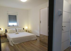 a white bedroom with a bed and a window at Apartment & Room Renee in Osijek