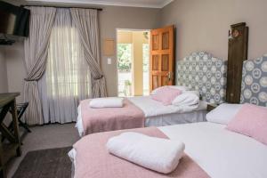 a room with three beds with pink and white sheets at Welverdiend Guesthouse and Venue in Piet Retief