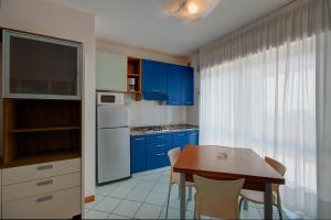 una cocina con armarios azules y una mesa con sillas en Residence Torre di Noe, en Bibione