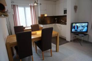 a kitchen with a wooden table with chairs and a television at Paradies 210 in Arosa