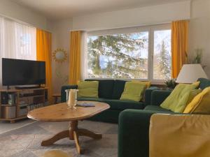 ein Wohnzimmer mit einem grünen Sofa und einem Tisch in der Unterkunft La Cabana 5 Arosa in Arosa
