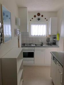 a white kitchen with a sink and a stove at La Cabana 5 Arosa in Arosa