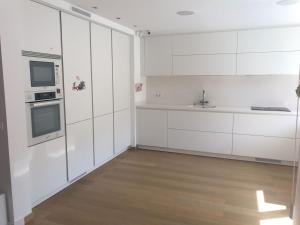 una cocina blanca con armarios blancos y fregadero en Nice Home, en Borgoñá