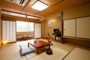 a living room with a table and a tv at Ichinomata Onsen Grand Hotel in Shimonoseki