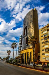 a building on the side of a street with palm trees at Lancaster Plaza Beirut in Beirut