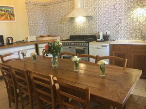 une cuisine avec une table en bois et des fleurs. dans l'établissement Le Mas Richard, à Générac