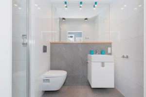 a white bathroom with a toilet and a sink at Przy Rozlewisku in Sarbinowo +74 photos