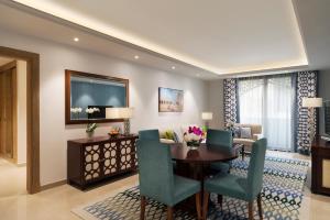 Al Najada Doha Hotel Apartments by Oaks في الدوحة: غرفة معيشة مع طاولة طعام وكراسي