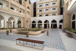 un bâtiment avec un banc au milieu d'une cour dans l'établissement Al Najada Doha Hotel Apartments by Oaks, à Doha